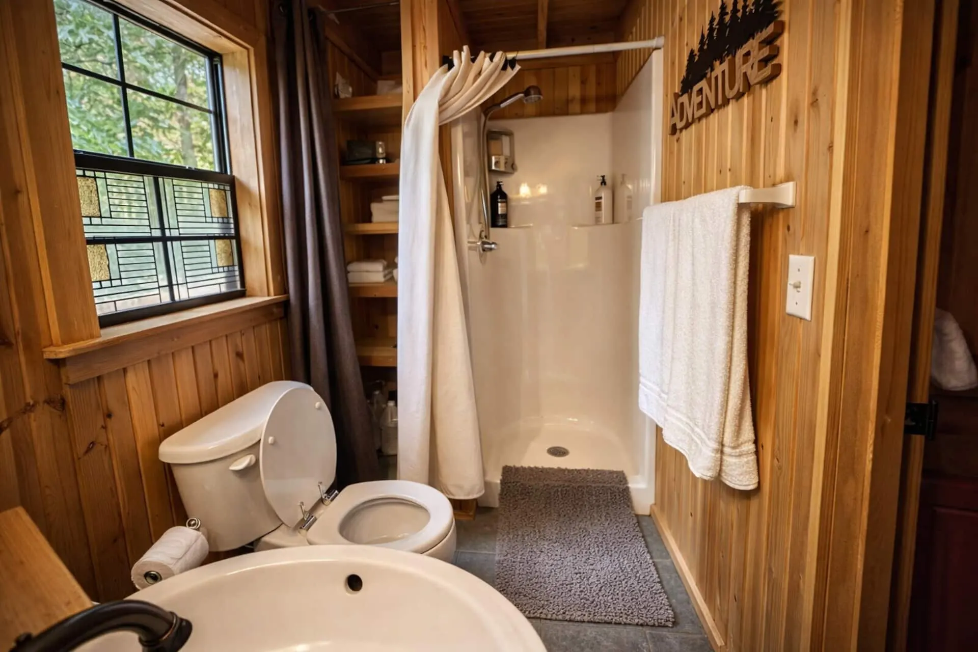 Bathroom with a walk-in shower, towel rail, open shelving and a window looking out into the woods